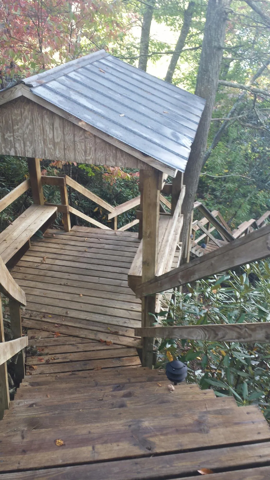 Metal roofed shelter over wooden steps on a wooded walkway — Skylight Repair & Installation work by our crew in Northfield